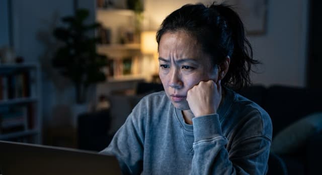 An NDIS provider looking worried at a laptop in low evening light - the moment many providers absorb the scope of the April 2026 reform package.